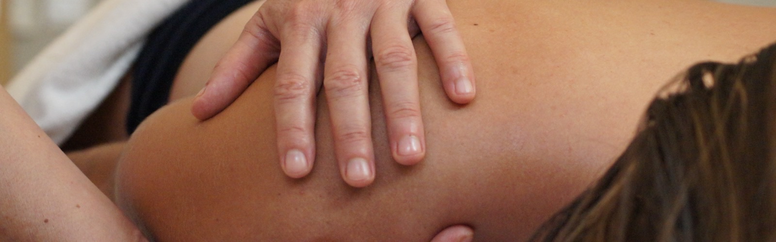 Massage énergétique : mains de la praticienne sur l’épaule